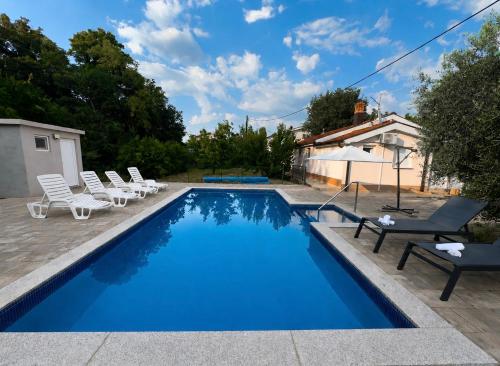 a swimming pool with lounge chairs and a house at Holiday Home Slap Koćuša in Ljubuški