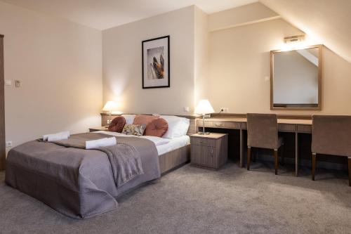 a bedroom with a bed and a desk with a mirror at Hotel Három Gúnár in Kecskemét