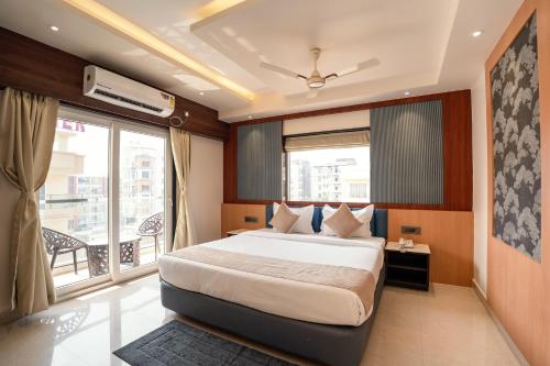 a bedroom with a large bed and a balcony at Trayee International in Digha