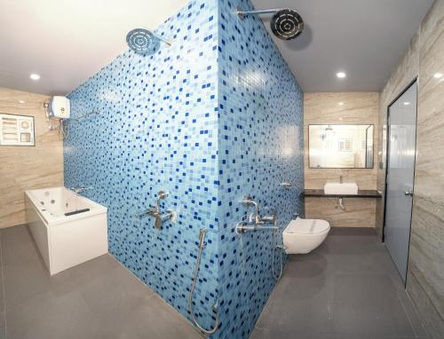 a bathroom with a blue tiled wall with a toilet and a sink at Trayee International in Digha