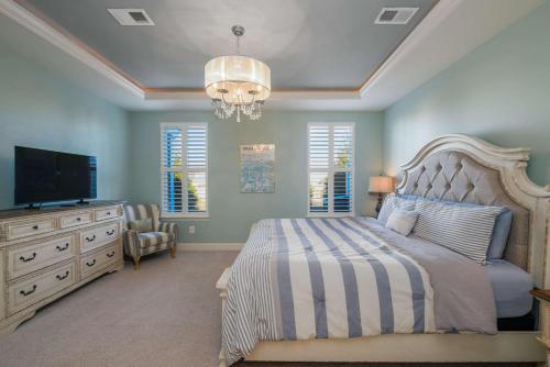 a bedroom with a bed and a television and a chandelier at Villa at Greys Neck - Close to Bethany Beach in Millville