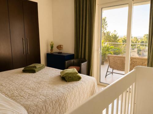 a bedroom with a bed and a balcony at Phos & Kipos Villa in Koskinou