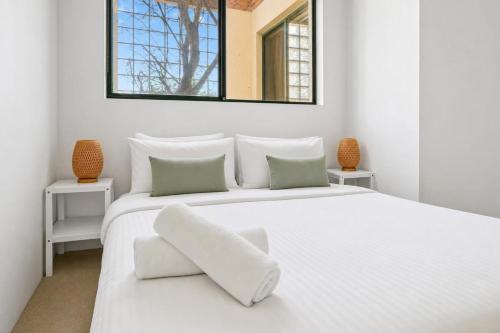 a white bedroom with a large white bed with a mirror at 2 Bedroom House Woolloomooloo in Sydney