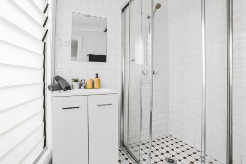 a white bathroom with a shower and a sink at 2 Bedroom House Woolloomooloo in Sydney