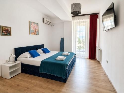 a bedroom with a bed with blue pillows and a television at MAMAIA SAMMERLAND APARTAMENT 3 camere in Mamaia