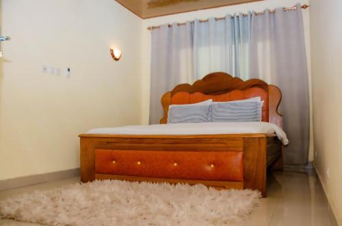 a bedroom with a wooden bed and a white curtain at Raoul Immobilier JDMK in Brazzaville