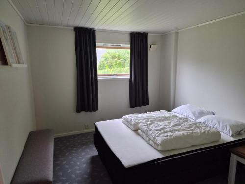 a bedroom with a white bed with a window at Sjarmerende hus i havgapet i Selje in Salt