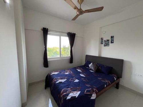 a bedroom with a bed with a ceiling fan and a window at Beruru Homes- 2BHK Apartment near Bengaluru Airport in Devanhalli