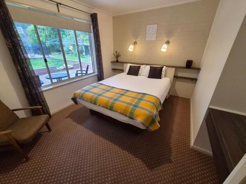 a bedroom with a bed and a window and a chair at Restaway Holiday Units in Porepunkah