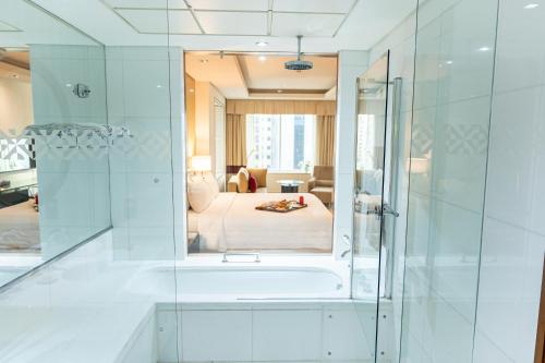 a bathroom with a bath tub and a bedroom at Majestic Premier Hotel Burdubai in Dubai