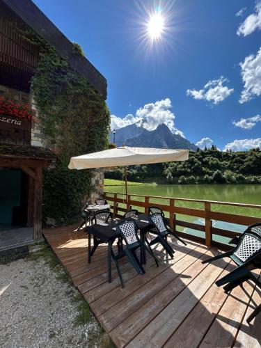 a deck with tables and chairs and an umbrella at Chalet Al Lago in San Vito di Cadore