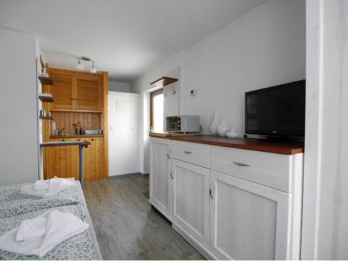 a kitchen with white cabinets and a flat screen tv at Bungalow in Bansin