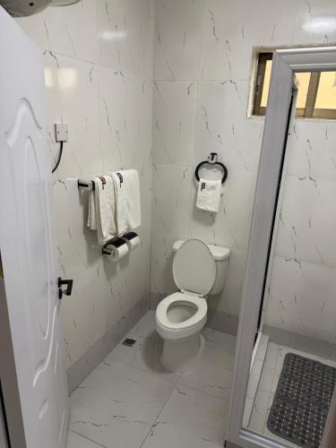 a white bathroom with a toilet and towels at The Stafford Lodge in Freetown