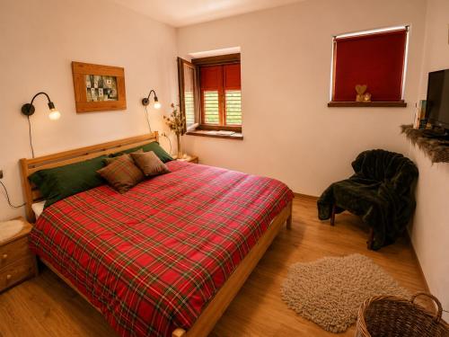 a bedroom with a bed with a plaid blanket and a chair at Casa Cappuccetto in Imer
