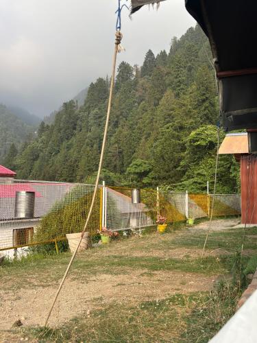 a fence in front of a mountain with trees at Himalayan Wooden Cottage camping & Cafe Dalhousie in Dalhousie