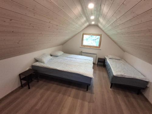 a attic bedroom with two beds and a window at Riverside Sauna House in Savala