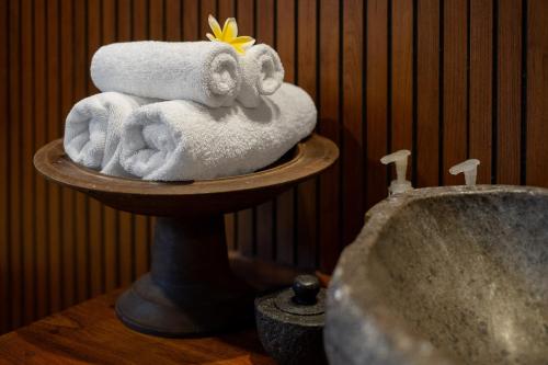 a stack of towels on a stand next to a sink at KERAMAN SUITE UBUD in Ubud