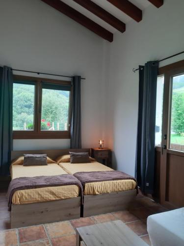two beds in a room with two windows at Eguzkitze Habitacion Rural Independiente in Abaltzisketa