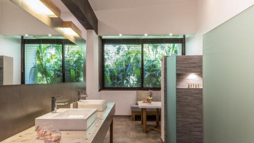 La salle de bains est pourvue de 2 lavabos et d'un grand miroir. dans l'établissement Cala Luna Boutique Hotel & Villas, à Tamarindo