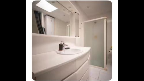 a white bathroom with a sink and a mirror at Maison orchidée in Nîmes