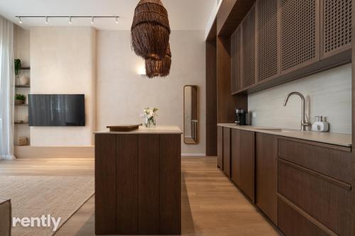 a kitchen with brown cabinets and a sink and a tv at Luxury Apartments And Studios At Sea Side By Rently in Eilat