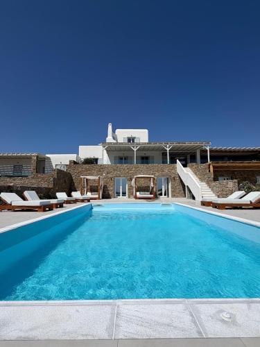 a large swimming pool with chairs and a house at Elia Horizon Mykonos in Elia Beach