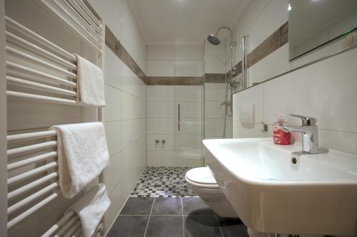 a white bathroom with a sink and a toilet at Hotel Mykonos in Eschweiler