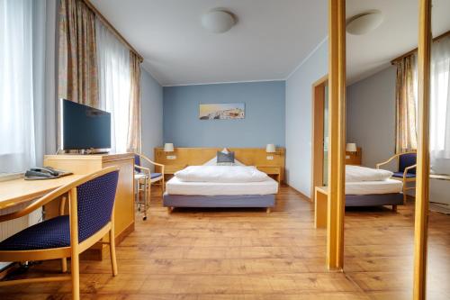 a hotel room with two beds and a desk at Hotel Mykonos in Eschweiler