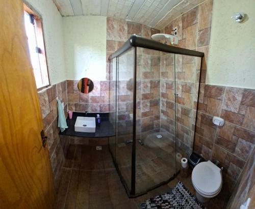 a bathroom with a shower with a toilet and a sink at Chalé Jardim Mágico in Milho Verde