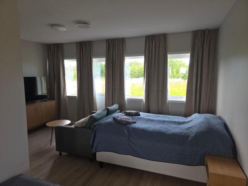 a bedroom with a bed and a couch and windows at Aurora Andøya Suites in Andøya