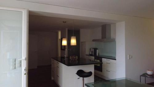 a kitchen with a counter and a stool in a room at Ferienwohnung am Bodensee - Ruhe,Natur und Golfgenuss in Lochau