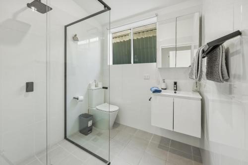a white bathroom with a shower and a toilet at Lovely Hidden Gem in Redcliffe in Redcliffe