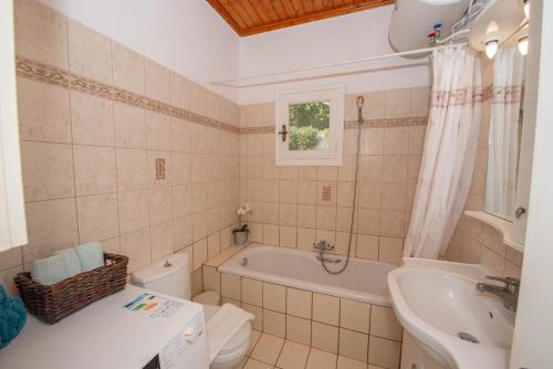 a bathroom with a tub and a toilet and a sink at Ilia's Holiday Home in Perítheia