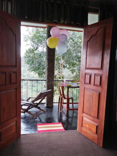an open door to a porch with a table and balloons at Will Guest Homestay in Ella