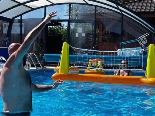 a man in the water in a swimming pool at Rajska Mierzeja , SAUNA , JAKUZZI ,BASEN Z PODGRZEWANĄ WODĄ , KLIMATYZACJA-OGRZEWANIE , PLAC ZABAW , ROWERY , TARAS in Sarbinowo