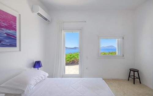 a white bedroom with a bed and a window at Sunset Flower Villa in Kástron