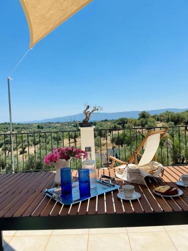 a wooden deck with a table with blue glasses at Horizon House, with Olive Grove and a small Vineyard in Amarynthos