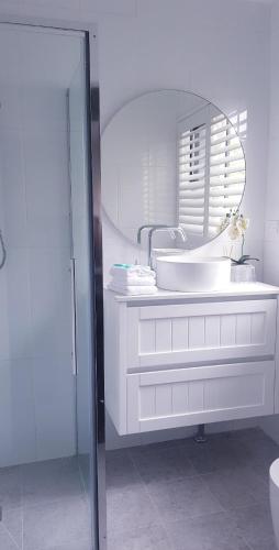a white bathroom with a sink and a mirror at Bay & Basin in Sanctuary Point