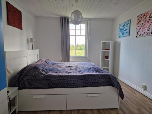 a white bedroom with a bed and a window at Manus Ferienwohnung in Brevik