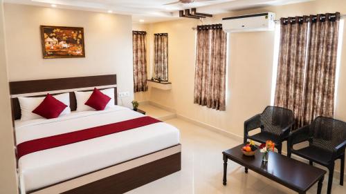a bedroom with a bed and a table and chairs at Hotel MountView Comforts in Tirupati