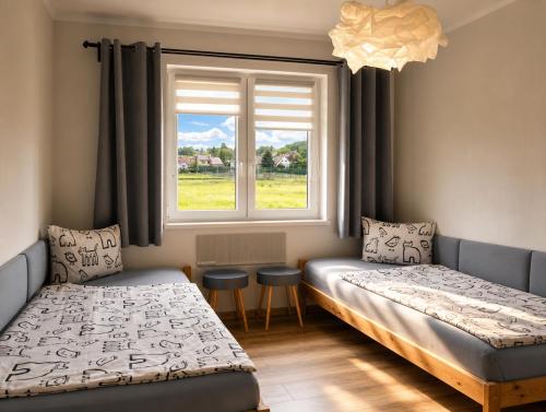 two beds in a room with a window at Śpij w Kudowie Apartament i pokoje gościnne in Kudowa-Zdrój