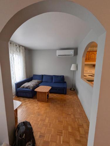 a living room with a blue couch and a table at Le Milka II in Longueuil