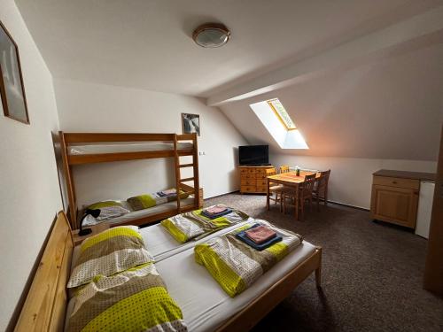 a bedroom with two bunk beds and a table at Penzion U Horejšů, Zadov - Churáňov in Stachy