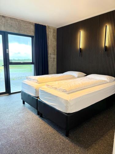 two beds in a hotel room with a large window at Seljavellir Guesthouse in Höfn