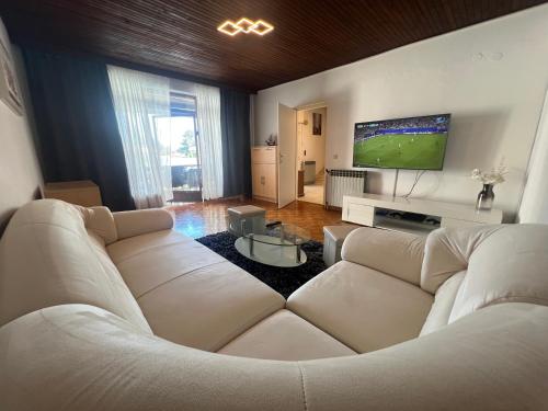 a living room with two white couches and a flat screen tv at Holiday Home Marković in Bibinje