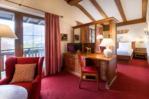 ein Schlafzimmer mit einem Bett und einem Schreibtisch mit Fernseher in der Unterkunft Hotel Bräu in Zell am Ziller