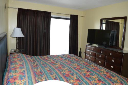 a bedroom with a bed with a television and a dresser at The Summit Condominiums in Panama City Beach