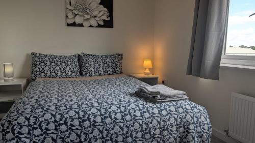 a bedroom with a bed with a blue and white comforter at NG Property in Glasgow