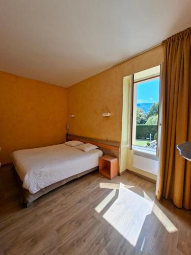 a bedroom with a bed and a large window at Logis Hotel Restaurant Mas de la Prairie in Le Vigan
