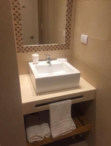 a bathroom with a sink and a mirror and towels at Departamentos Playa Quequen in Quequén
